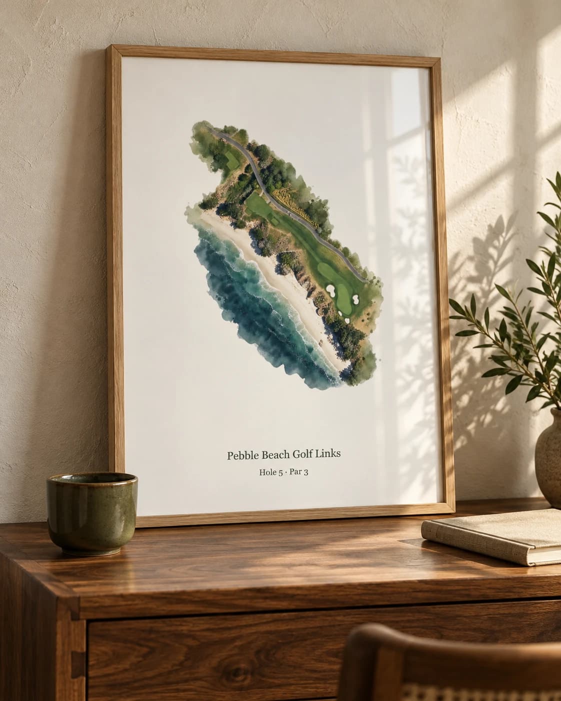 Pebble Beach hole 5 in an oak frame on a walnut desk, beside an olive ceramic cup